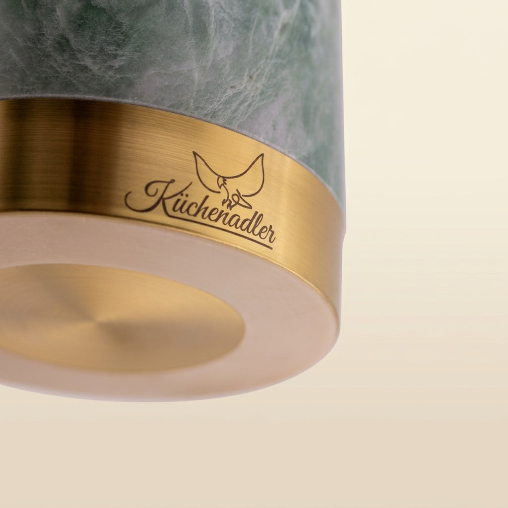 Detailaufnahme der Unterseite des Küchenadler Green Ming Marmormörsers mit ringförmigem Anti-Rutsch-Pad und gebürstetem Messingsockel mit Logo.